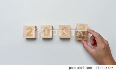 Man hand flipping wooden block cube from 2023 to 2024. Starting to new year, business target achievement 110803526