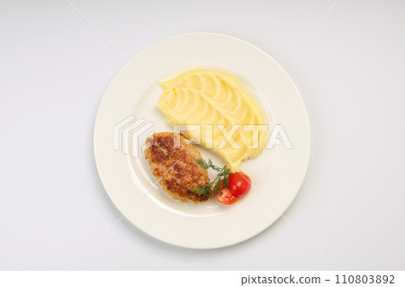 Dinner. Fried cutlet in mashed potatoes on a white plate and a white background Dinner. Fried cutlet in mashed potatoes on a white plate and a white background 110803892