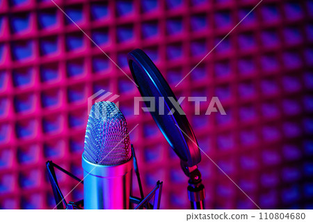 Professional studio microphone against acoustic foam panel background in neon light 110804680
