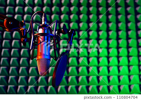 Professional studio microphone against acoustic foam panel background in neon light 110804704