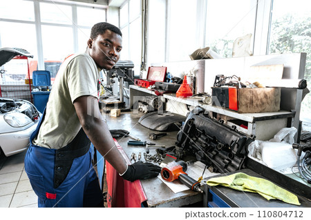 Young african mechanic in uniform working in a car service shop 110804712