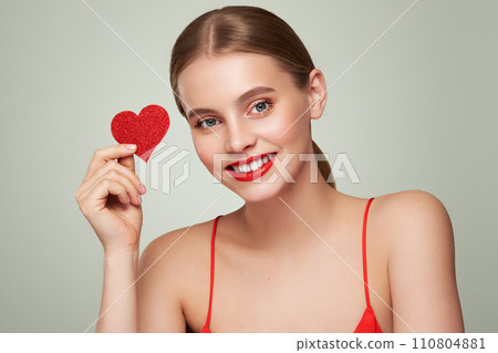 Beautiful woman holding an artificial red heart 110804881