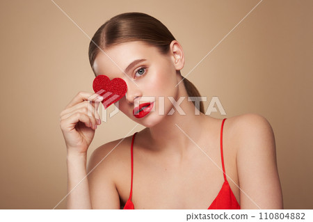 Beautiful woman holding an artificial red heart 110804882