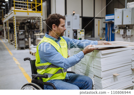 Portrait of man in wheelchair working in modern industrial factory, scanning with scanner. Concept of workers with disabilities, accessible workplace for employees with mobility impairment. 110806944