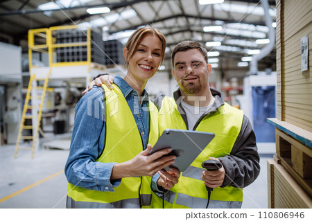 Young man with Down syndrome working in warehouse, female colleague teaching him scan products with scanner. Concept of workers with disabilities, support in workplace. 110806946