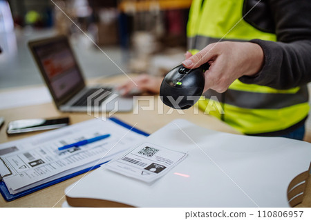 Female warehouse worker holding scanner, scanning the barcodes on products in warehouse, checking in laptop. Warehouse manager using warehouse scanning system. Female warehouse worker holding scanner, scanning the barcodes on products in warehouse, checking in laptop. Warehouse manager using warehouse scanning system. 110806957