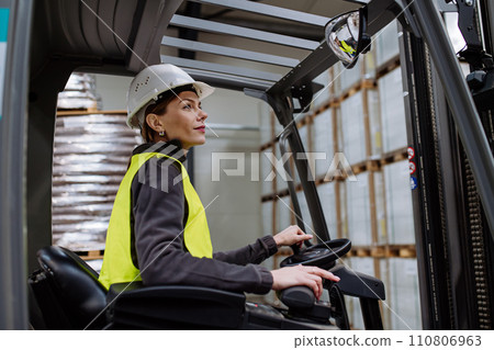 Female warehouse worker driving forklift. Warehouse worker preparing products for shipmennt, delivery, checking stock in warehouse. Female warehouse worker driving forklift. Warehouse worker preparing products for shipmennt, delivery, checking stock in warehouse. 110806963