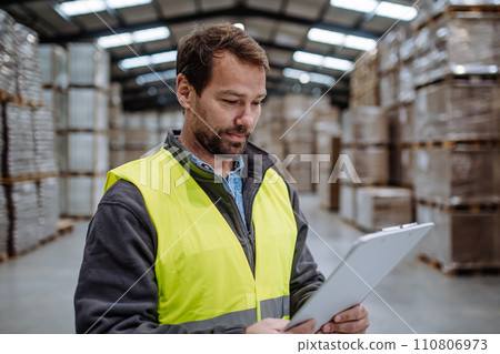 Portrait of warehouseman with clipboard checking delivery, stock in warehouse. Warehouse worker preparing products for shipment. Portrait of warehouseman with clipboard checking delivery, stock in warehouse. Warehouse worker preparing products for shipment. 110806973