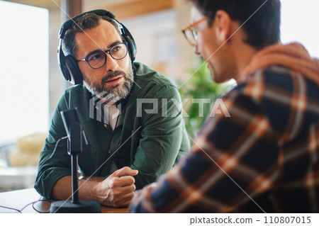 Male friends doing video podcast, talking about difficult topics, sharing sad, hurtful stories. Influencers making live video for social media, creating online content. Male friends doing video podcast, talking about difficult topics, sharing sad, hurtful stories. Influencers making live video for social media, creating online content. 110807015