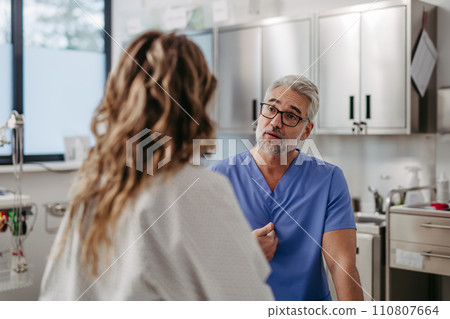 Doctor showing female patient MRI scan on tablet, discussing test result in emergency room. 110807664