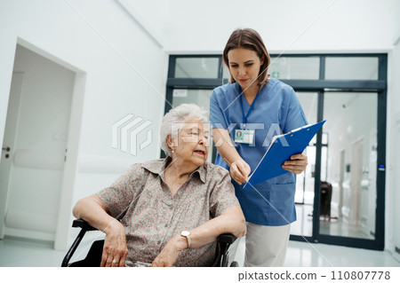 Nurse talking with senior woman, admitting a patient to the hospital, filling documents. Discharging of elderly patient. after surgery. Nurse talking with senior woman, admitting a patient to the hospital, filling documents. Discharging of elderly patient. after surgery. 110807778