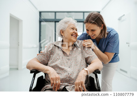 Portrait of nurse and senior patient talking in hospital corridor. Emotional support for elderly woman. 110807779