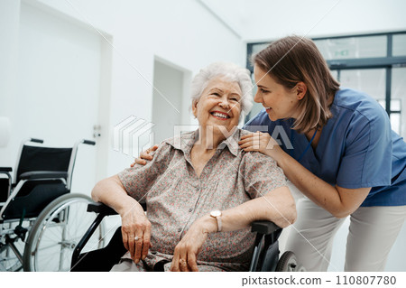 Portrait of nurse and senior patient talking in hospital corridor. Emotional support for elderly woman. 110807780