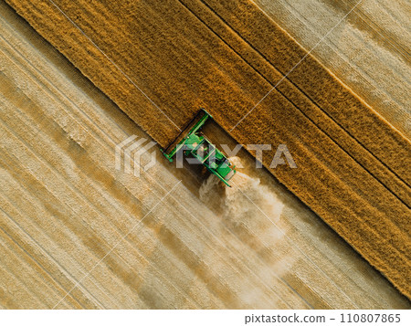 Aerial view of a harvester working in a field. Agriculture and cultivation of industrial farms. Agribusiness. Aerial view of a harvester working in a field. Agriculture and cultivation of industrial farms. Agribusiness. 110807865