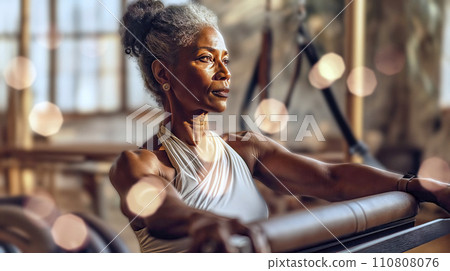 Elderly Black Woman with Curly Gray Hair Exercising on Pilates Machine 110808076