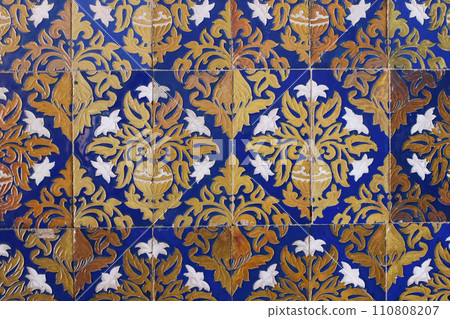 Detail of vintage Spanish ceramic tiles.Baroque styled pattern with lilies flowers, vases. Old blue azulejo facade with floral ornaments. Antique building detail. Artistic hand drawn decorative 110808207