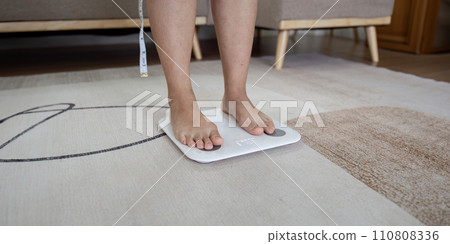 Over weight women weigh on scales to see results after exercise, healthy at home 110808336