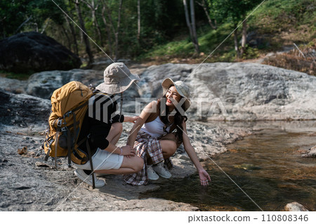 Happy LGBT Lesbian couple Travelers Hiking with Backpacks in waterfall Trail. LGBT Lesbian Couple Hikers with backpacks walks in mountains in vacation 110808346