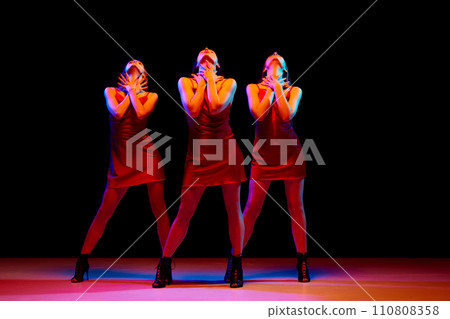 Three passionate elegant women in red dresses dancing, performing against black background in neon light Three passionate elegant women in red dresses dancing, performing against black background in neon light 110808358