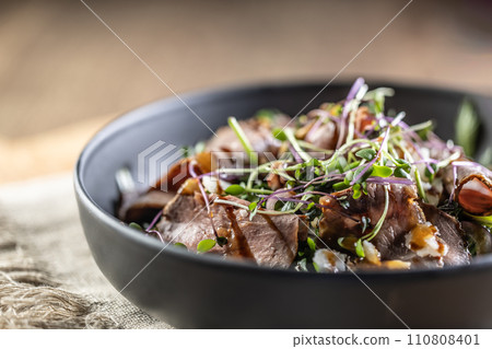 Roast beef salad with herbs and balsamic sauce in the style of a bowl on a restaurant table - Close up 110808401