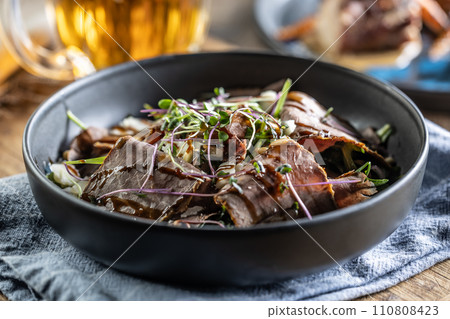 Roast beef salad with herbs and balsamic sauce in the style of a bowl on a restaurant table - Close up 110808423