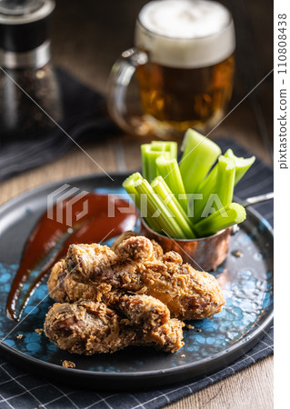 Fried chicken legs with celery sticks and draft beer on plate in pub or restaurant Fried chicken legs with celery sticks and draft beer on plate in pub or restaurant 110808438