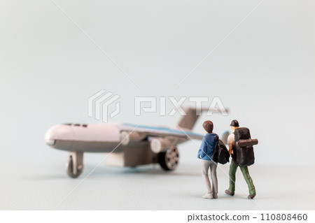 Miniature people, travelers embarks on a delightful vacation, gleefully boarding a tiny airplane 110808460