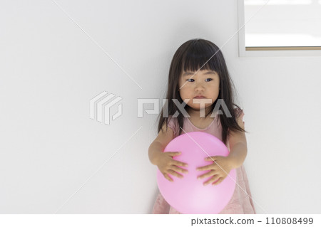Bored girl playing with balloons (3 years old, Japanese) 110808499
