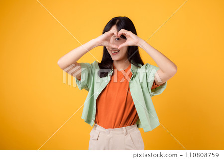 healthcare and wellness guided by an Asian woman in her 30s. Let her heart hand gesture on a vibrant yellow background inspire your journey towards body wellness healthcare and wellness guided by an Asian woman in her 30s. Let her heart hand gesture on a vibrant yellow background inspire your journey towards body wellness 110808759