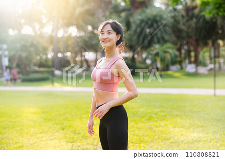 Experience the joy of wellness living as a happy, beautiful Asian woman in her 30s smiles at the camera in a park at sunset. Embrace the concept of well-being. Experience the joy of wellness living as a happy, beautiful Asian woman in her 30s smiles at the camera in a park at sunset. Embrace the concept of well-being. 110808821
