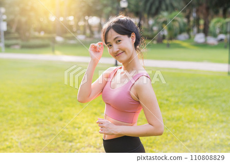 Experience the joy of wellness living as a happy young 30s Asian woman smiles at the camera in a park at sunset. Embrace the beauty of nature and a healthy lifestyle. Experience the joy of wellness living as a happy young 30s Asian woman smiles at the camera in a park at sunset. Embrace the beauty of nature and a healthy lifestyle. 110808829