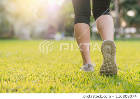 jogger woman. close up person training sport runner young female shoe on grasses in public park. fitness leg and foot exercise athlete. marathon in nature. active healthy lifestyle workout concept. 110809074