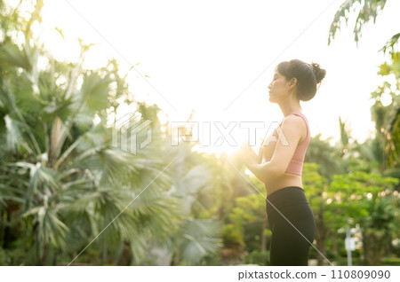 concept of wellness and well being fit 30s young Asian woman in pink sportswear plays yoga and stretches muscles. Embrace healthy outdoor lifestyle with fitness yoga girl in public park at sunset. concept of wellness and well being fit 30s young Asian woman in pink sportswear plays yoga and stretches muscles. Embrace healthy outdoor lifestyle with fitness yoga girl in public park at sunset. 110809090