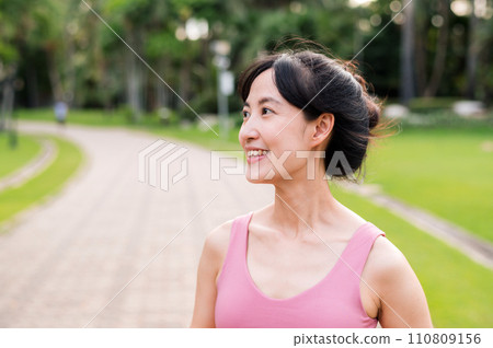 Woman jogger. young asian female happy smile wearing pink sportswear running in public park. Healthcare wellness concept. Woman jogger. young asian female happy smile wearing pink sportswear running in public park. Healthcare wellness concept. 110809156