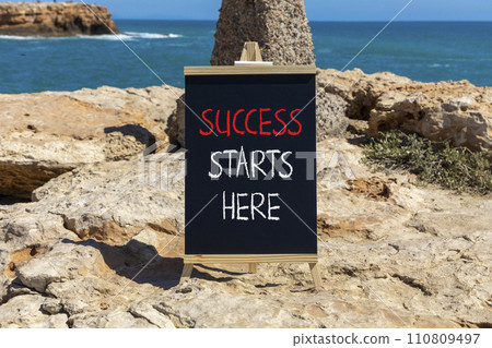 Success starts here symbol. Concept word Success starts here on beautiful black blackboard. Beautiful stone beach sea blue sky background. Business motivational success starts here concept. Copy space Success starts here symbol. Concept word Success starts here on beautiful black blackboard. Beautiful stone beach sea blue sky background. Business motivational success starts here concept. Copy space 110809497