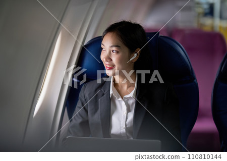 Successful young asian business woman sits in airplane cabin plane and working from anywhere. Flying at first class 110810144