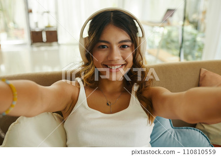 Happy teenage girl in headphones video calling her friend or family members Happy teenage girl in headphones video calling her friend or family members 110810559