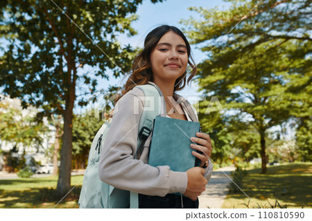 Portrait of smiling schoolgirl with students books in hands 110810590