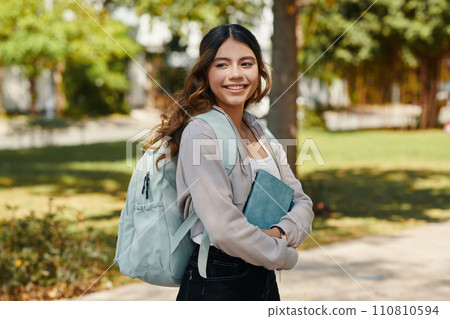 Portrait of smiling high school student with backpack and planner standing on school campus 110810594