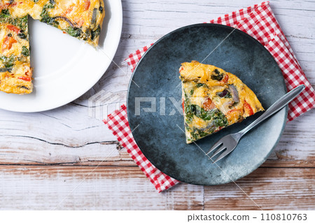 Italian Frittata made with spinach, tomatoes, onion and peppers on white wooden table Italian Frittata made with spinach, tomatoes, onion and peppers on white wooden table 110810763