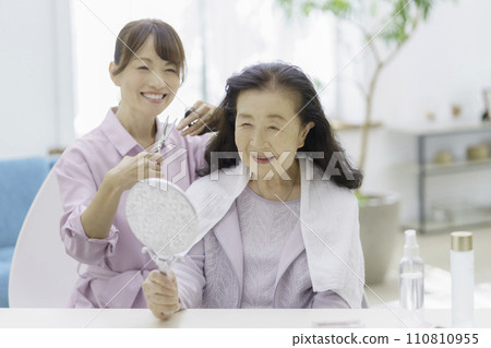 Senior woman receiving haircut at home 110810955