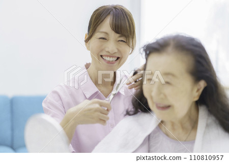 Senior woman receiving haircut at home 110810957