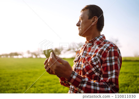 Farmer working with digital tablet in field at sunset. Checking wheat field. Agriculture concept. 110811030