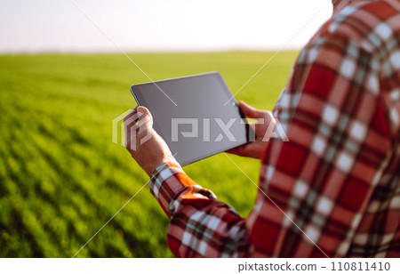 Tablet in the hands of a farmer. Smart farm. Farmer checking his crops on an agricultural field. Tablet in the hands of a farmer. Smart farm. Farmer checking his crops on an agricultural field. 110811410