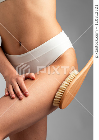 Closeup on woman scrubbing her hips with dry brush Closeup on woman scrubbing her hips with dry brush 110812521