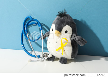 A stethoscope with a toy penguin and a yellow ribbon 110812765