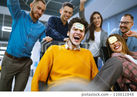 Young cheerful business people racing on office chairs and laughing. Funny activity 110812848