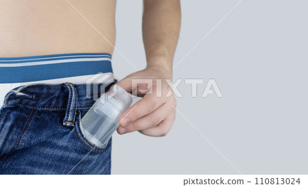 Bottle intimate lubricants. The man has intimate gel in his pocket. A male torso with slightly open trousers showing readiness for sex. Plastic bottle with lubricant 110813024