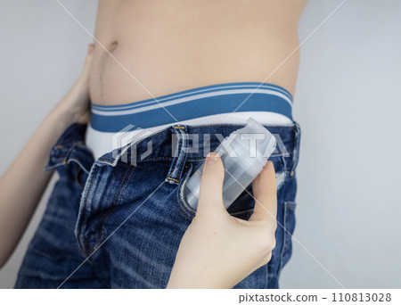 Bottle intimate lubricants. The man has intimate gel in his pocket. A male torso with slightly open trousers showing readiness for sex. Plastic bottle with lubricant. Women hands on the body Bottle intimate lubricants. The man has intimate gel in his pocket. A male torso with slightly open trousers showing readiness for sex. Plastic bottle with lubricant. Women hands on the body 110813028