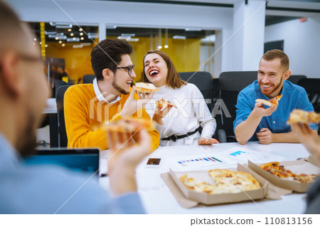 Cheerful diverse employees eating pizza together during break in office. Concept of business. Cheerful diverse employees eating pizza together during break in office. Concept of business. 110813156